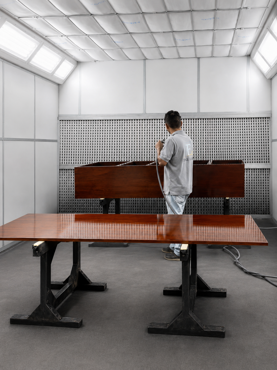 Applying high-gloss lacquer to mahogany panels and table surface in a controlled spray environment